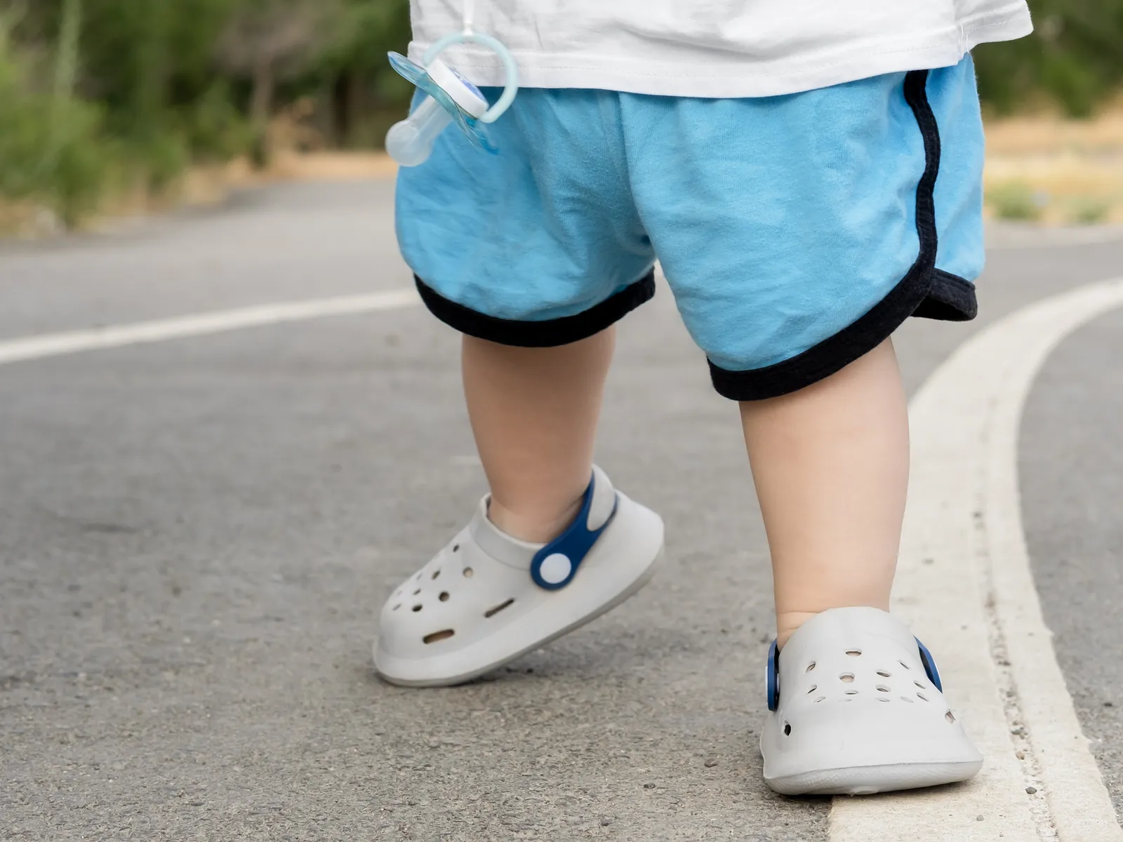 A toddler standing outdoors, seen from the knees down