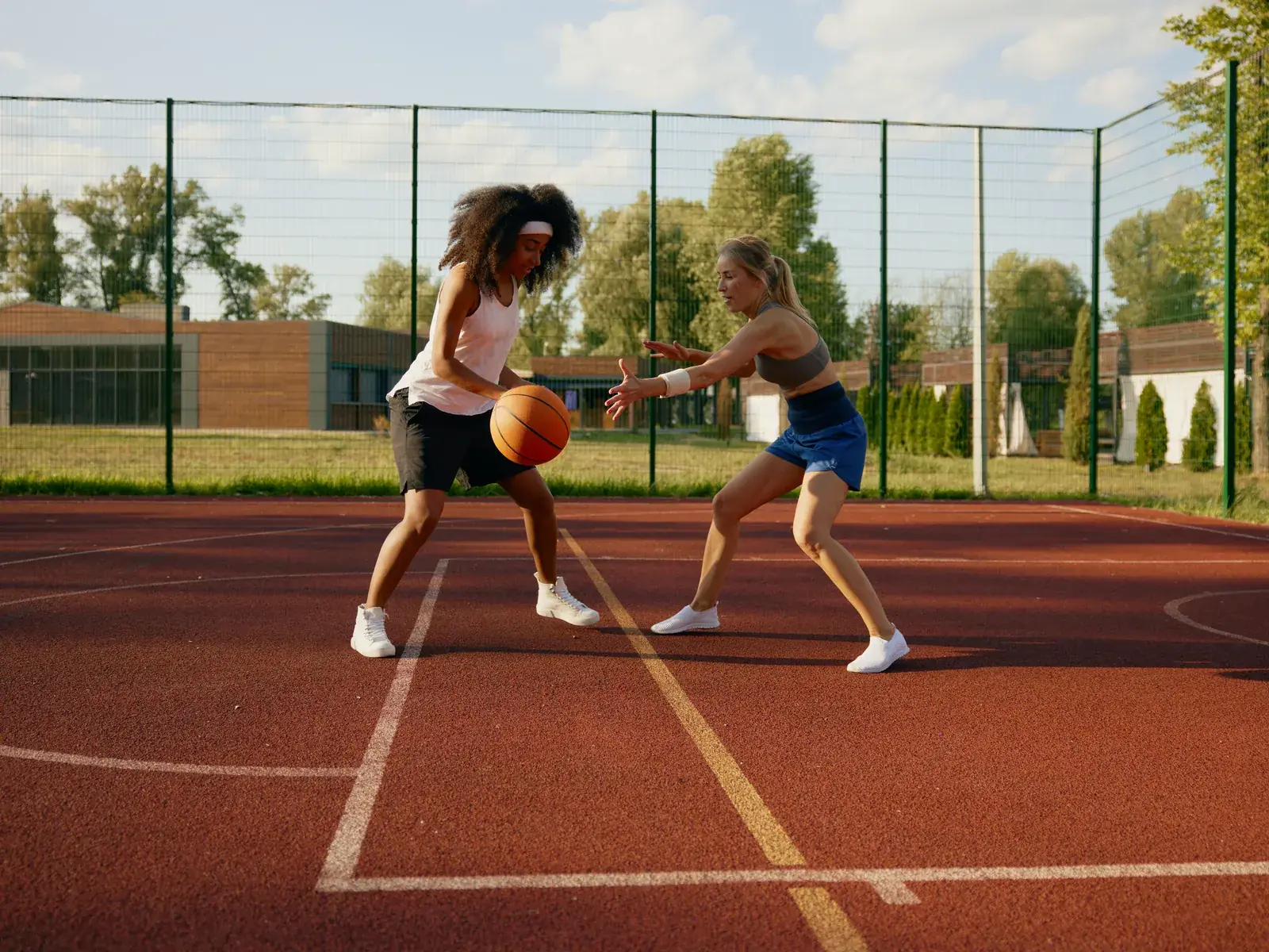 Two teenagers playing basketball on an outdoor court