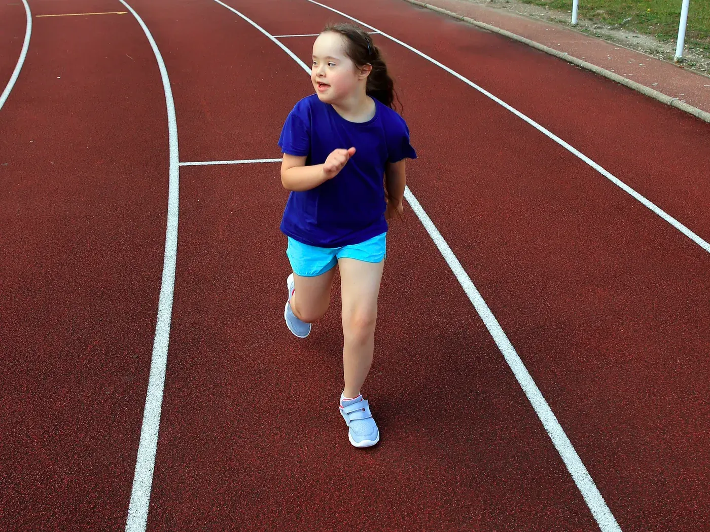 A young girl running on an outdoor athletics track